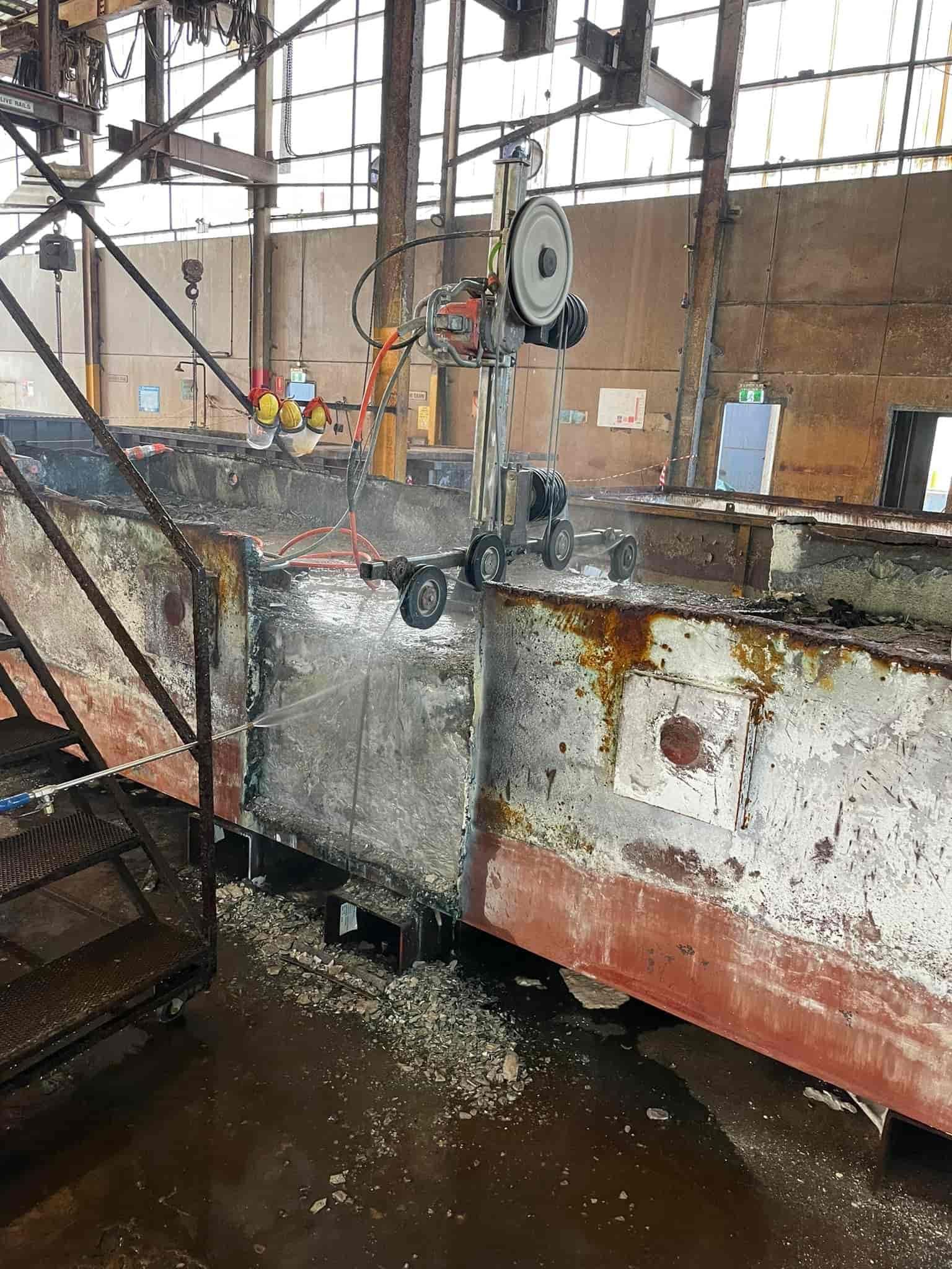 A machine is cutting a piece of metal in a factory — Newcastle Cut & Drill In Boolaroo, NSW