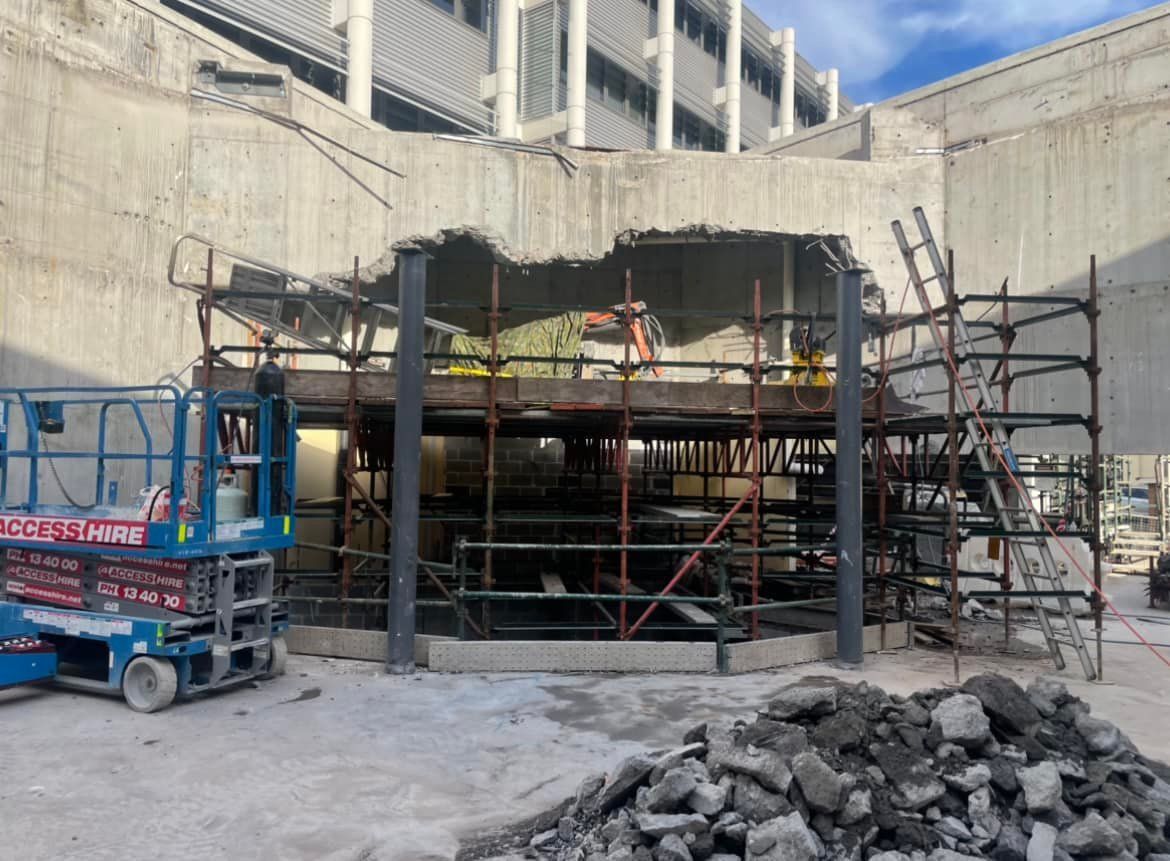 A construction site with a crane and scaffolding in front of a building under construction — Newcastle Cut & Drill In Boolaroo, NSW