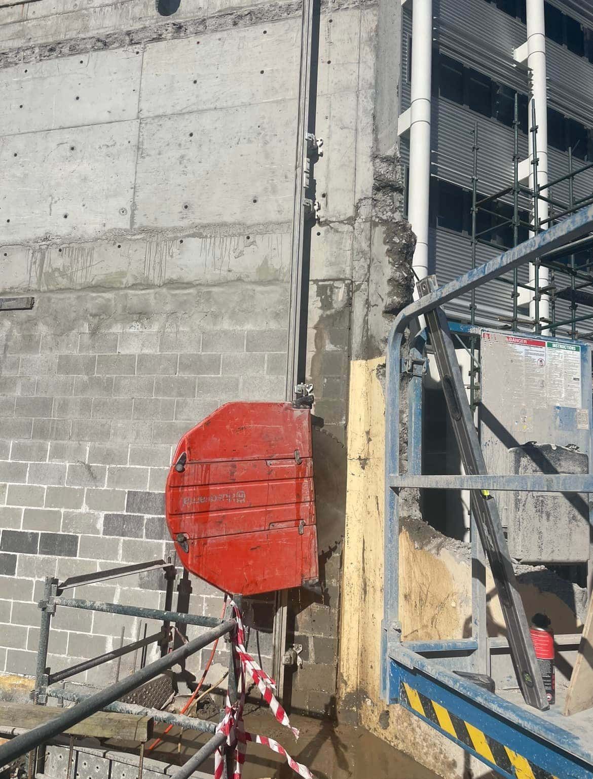 A red bucket is being used to cut a hole in a concrete wall — Newcastle Cut & Drill In Boolaroo, NSW