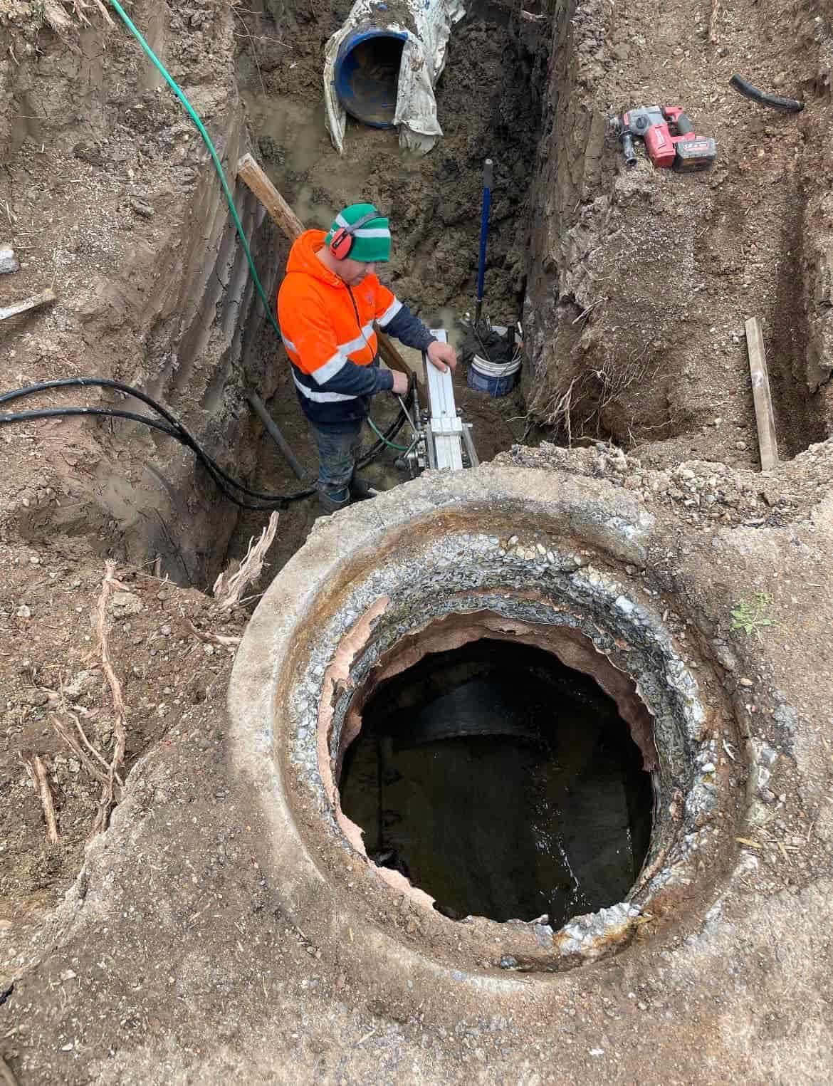 A man is working on a pipe in a hole in the ground — Newcastle Cut & Drill In Boolaroo, NSW
