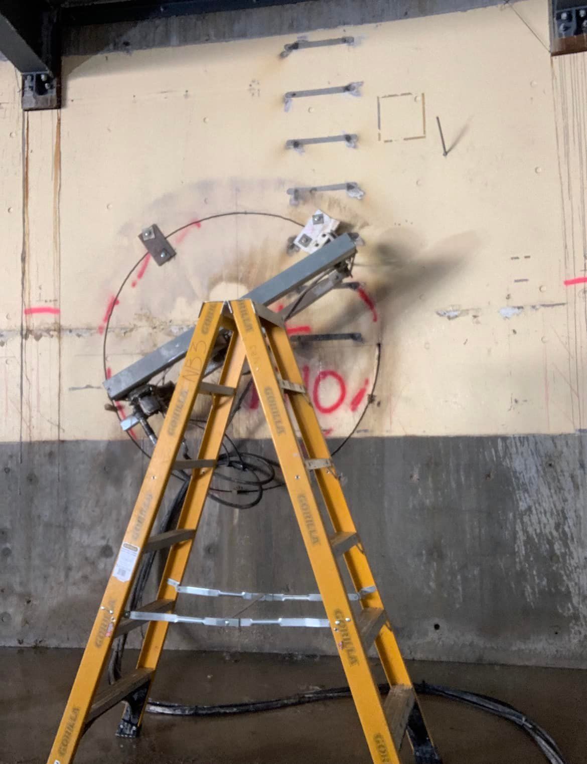 A yellow ladder is sitting in front of a wall with the number 10 written on it — Newcastle Cut & Drill In Boolaroo, NSW