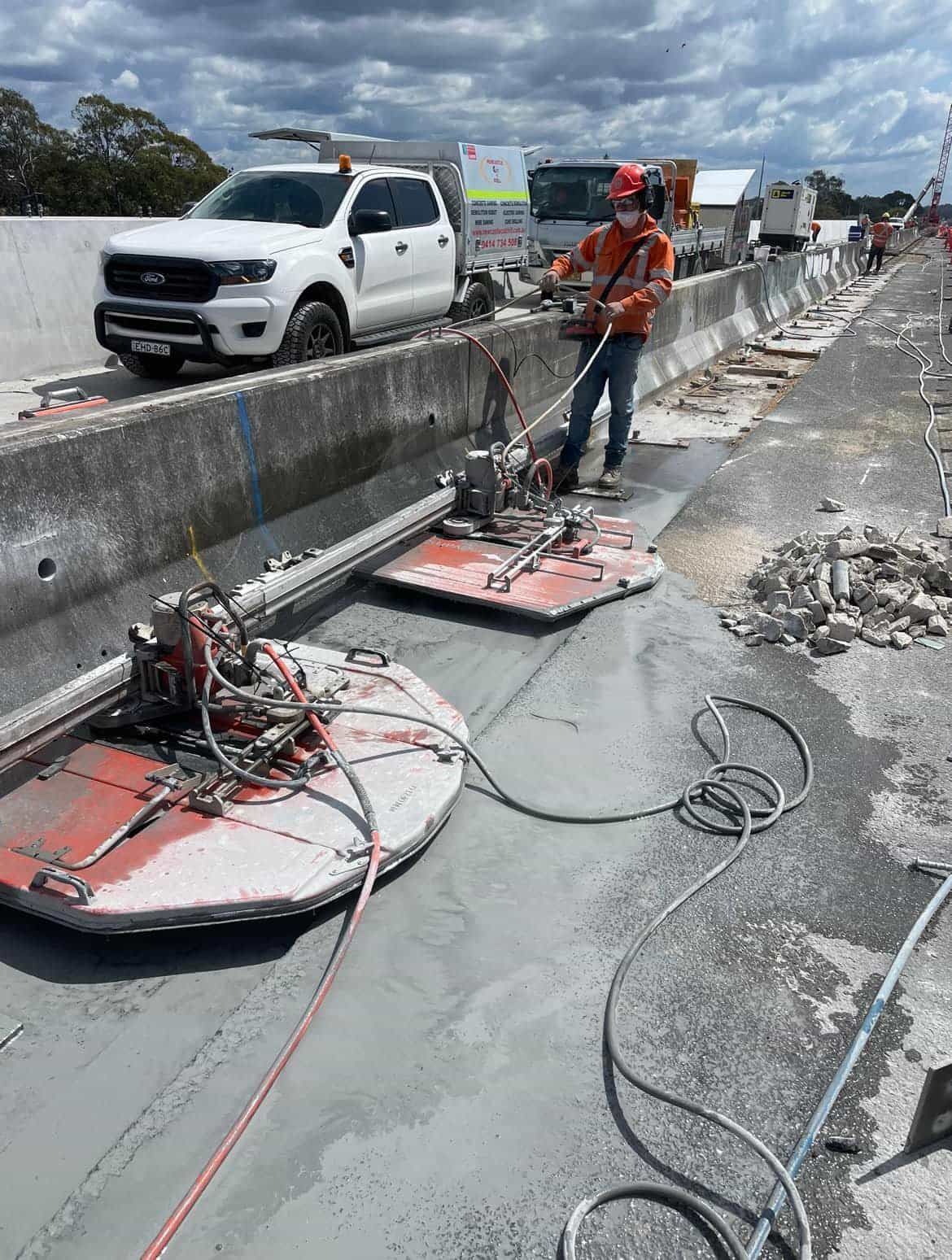 A man is cutting concrete on a highway with a machine — Newcastle Cut & Drill In Boolaroo, NSW