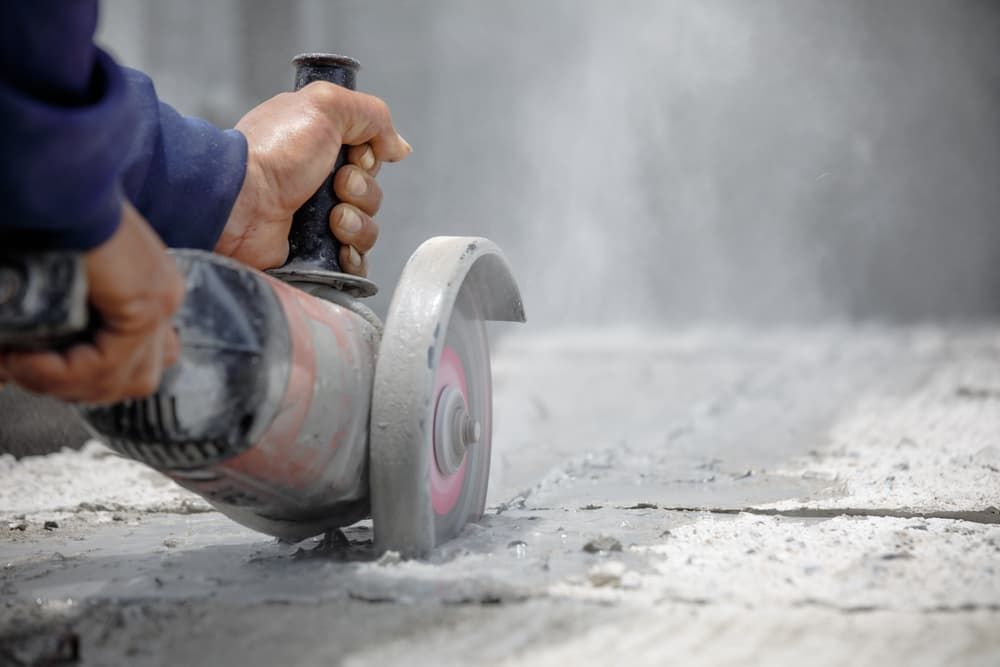 A man is cutting a piece of concrete with a grinder — Newcastle Cut & Drill In Boolaroo, NSW