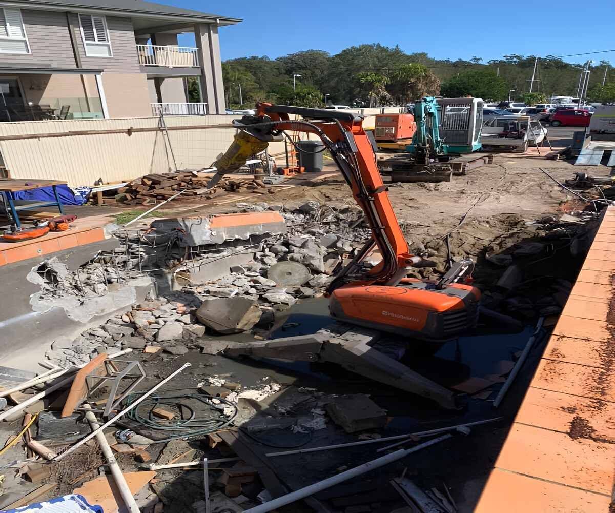 A Large Orange Excavator Is Sitting On Top Of A Pile Of Rocks — Newcastle Cut & Drill In Boolaroo, NSW