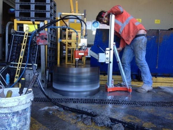 A Man Is Using A Machine To Cut A Hole In The Ground — Newcastle Cut & Drill In Boolaroo, NSW