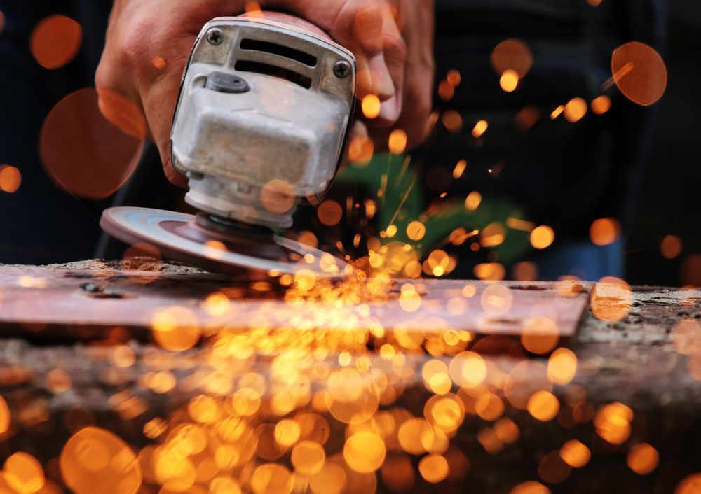 A Person Is Grinding A Piece Of Metal With Sparks Coming Out Of It — Newcastle Cut & Drill In Boolaroo, NSW