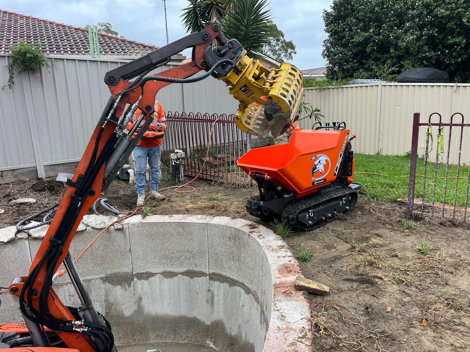 A Robotic Excavator Inside a pool loading out conrete cuts — Newcastle Cut & Drill In Boolaroo, NSW