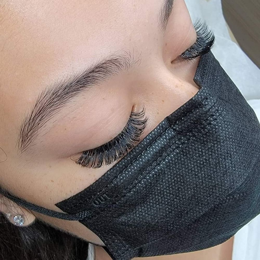 A woman wearing a black face mask with long eyelashes.