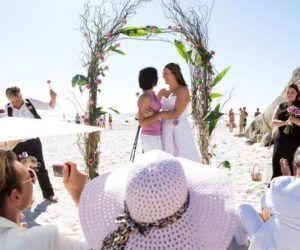 A bride and groom are getting married in a field with mountains in the background.