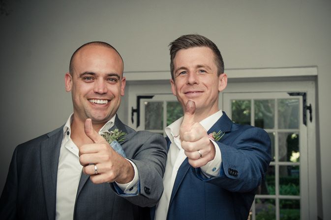 Two men in suits are giving a thumbs up sign.