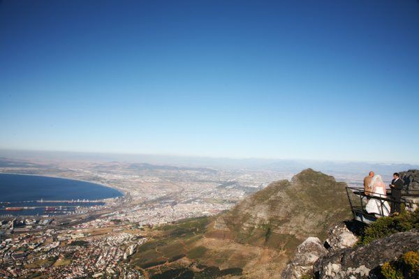A couple of people standing on top of a mountain overlooking a city.