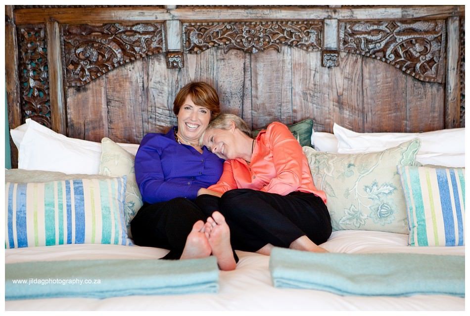 Two women are sitting on a bed hugging each other.