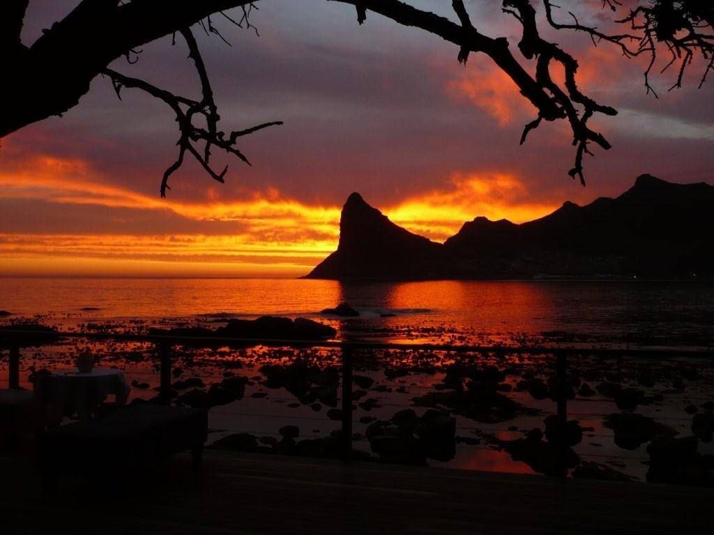 A sunset over a body of water with mountains in the background