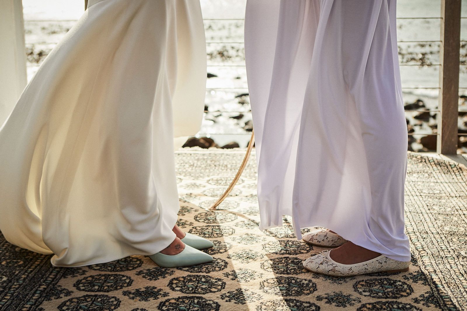 Two women in white dresses are standing next to each other on a rug.