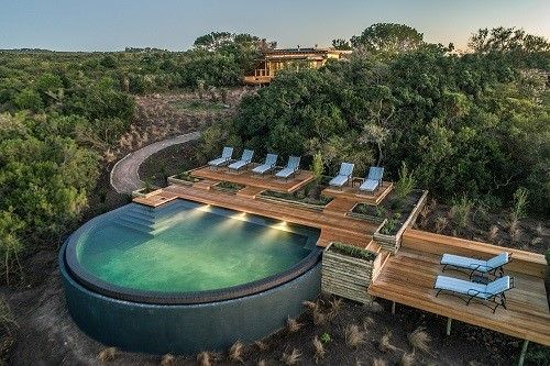 An aerial view of a large swimming pool surrounded by trees and chairs.