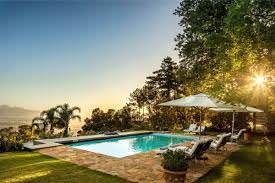 A large swimming pool surrounded by chairs and umbrellas in a backyard.