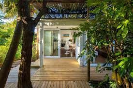 A house with a sliding glass door and a wooden deck surrounded by trees.