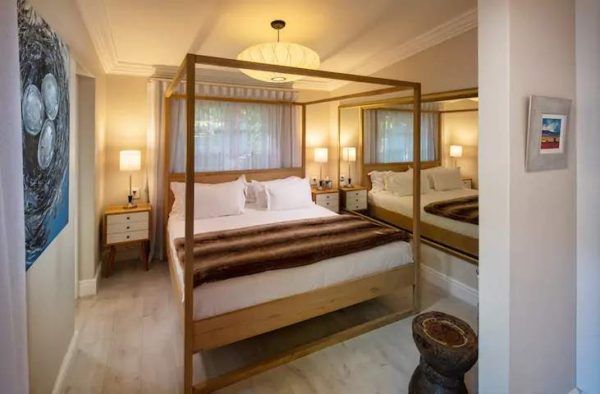 A bedroom with a four poster bed and a mirror.