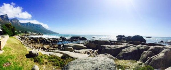 A blurry picture of a beach with rocks and mountains in the background.