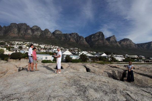 A group of people standing on top of a rocky hill with mountains in the background
