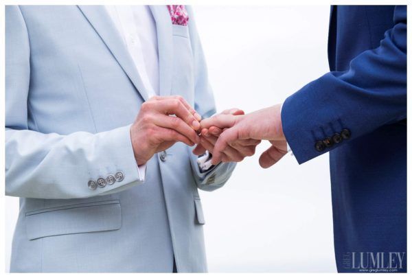 A man putting a wedding ring on another man 's finger