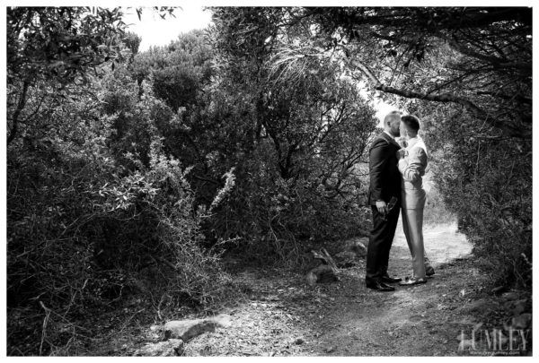 A black and white photo of a man and woman standing on a path in the woods.