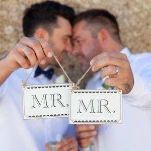 A bride and groom kissing at their wedding ceremony in front of a crowd of people.