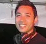 Smiling person wearing headphones against a red background, in a low-resolution photo.