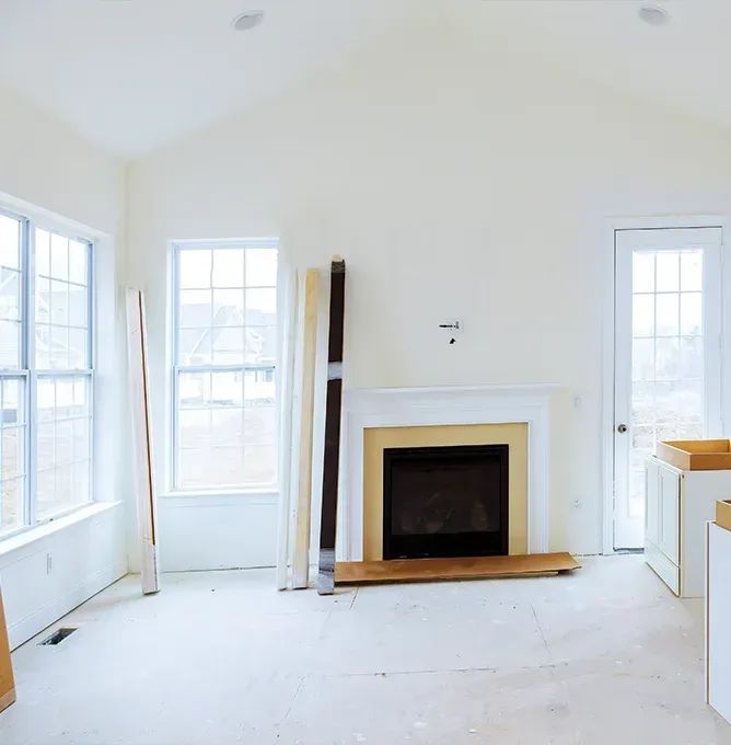 Bright white room with fireplace, tall windows, and a door, mostly empty and unfinished