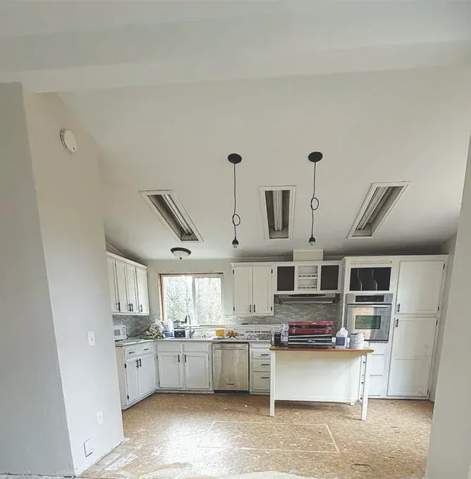Bright kitchen with white cabinets, island, and tiled floor in a spacious, empty room