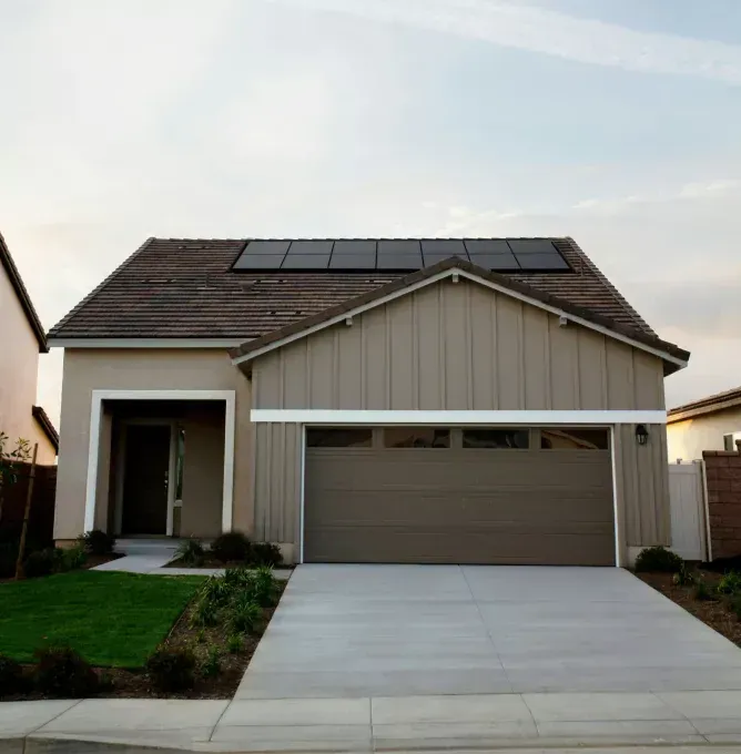 Modern suburban house with gray garage, front driveway, and solar panels on the roof