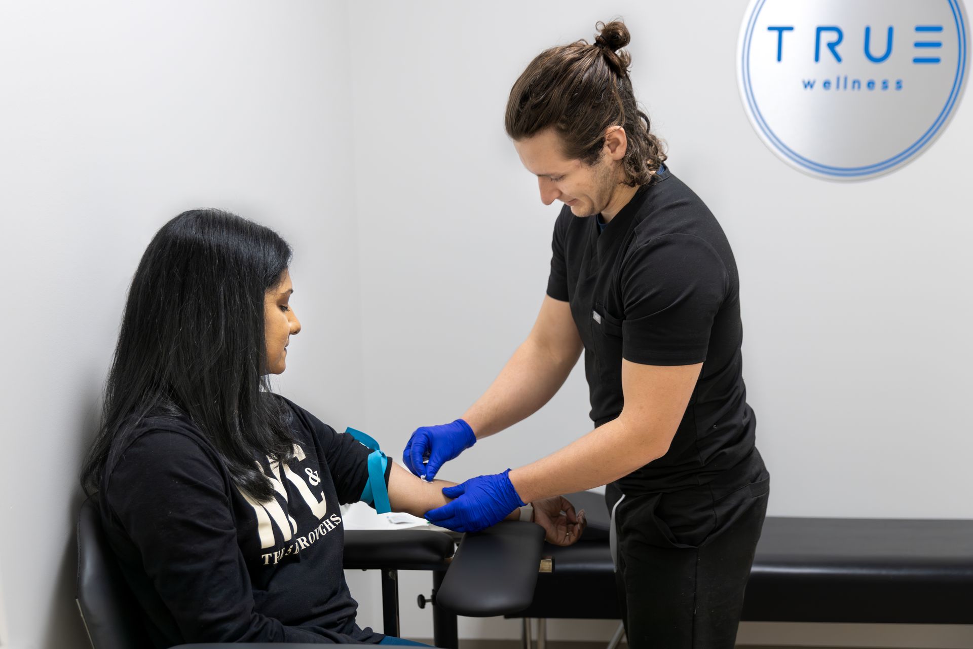 A doctor examines a woman's bandaged arm in a medical setting.