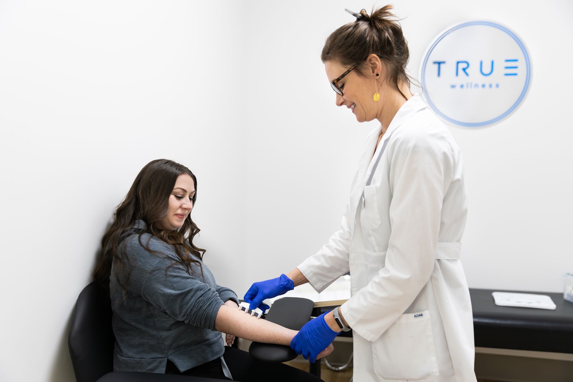 A medical professional draws blood from a patient's arm at a clinic.