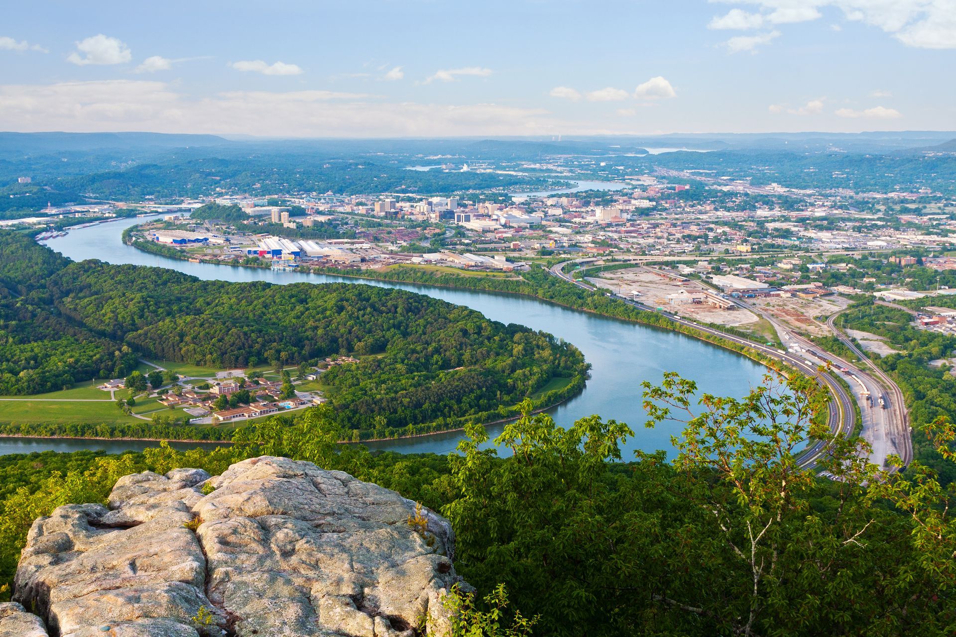 An aerial view of a river surrounded by trees and a city.