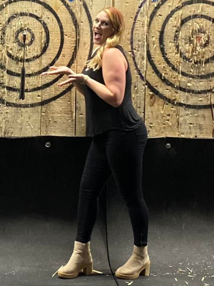 A woman is standing in front of a wooden target.