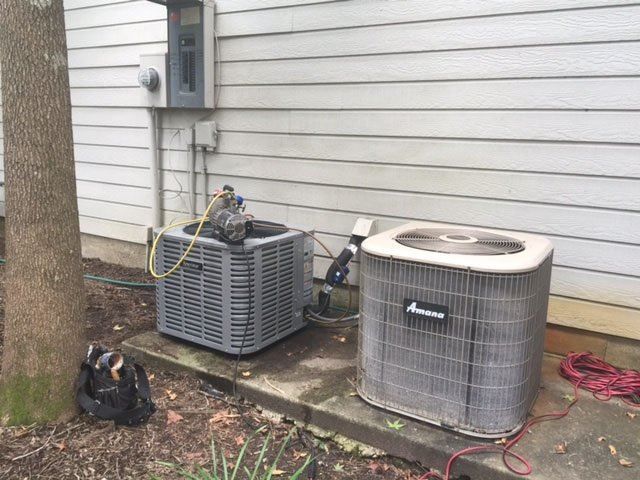 Two air conditioners are sitting on the side of a house.