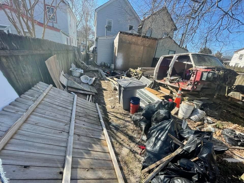 Overflowing cardboard boxes and trash piled in front of a white garage door