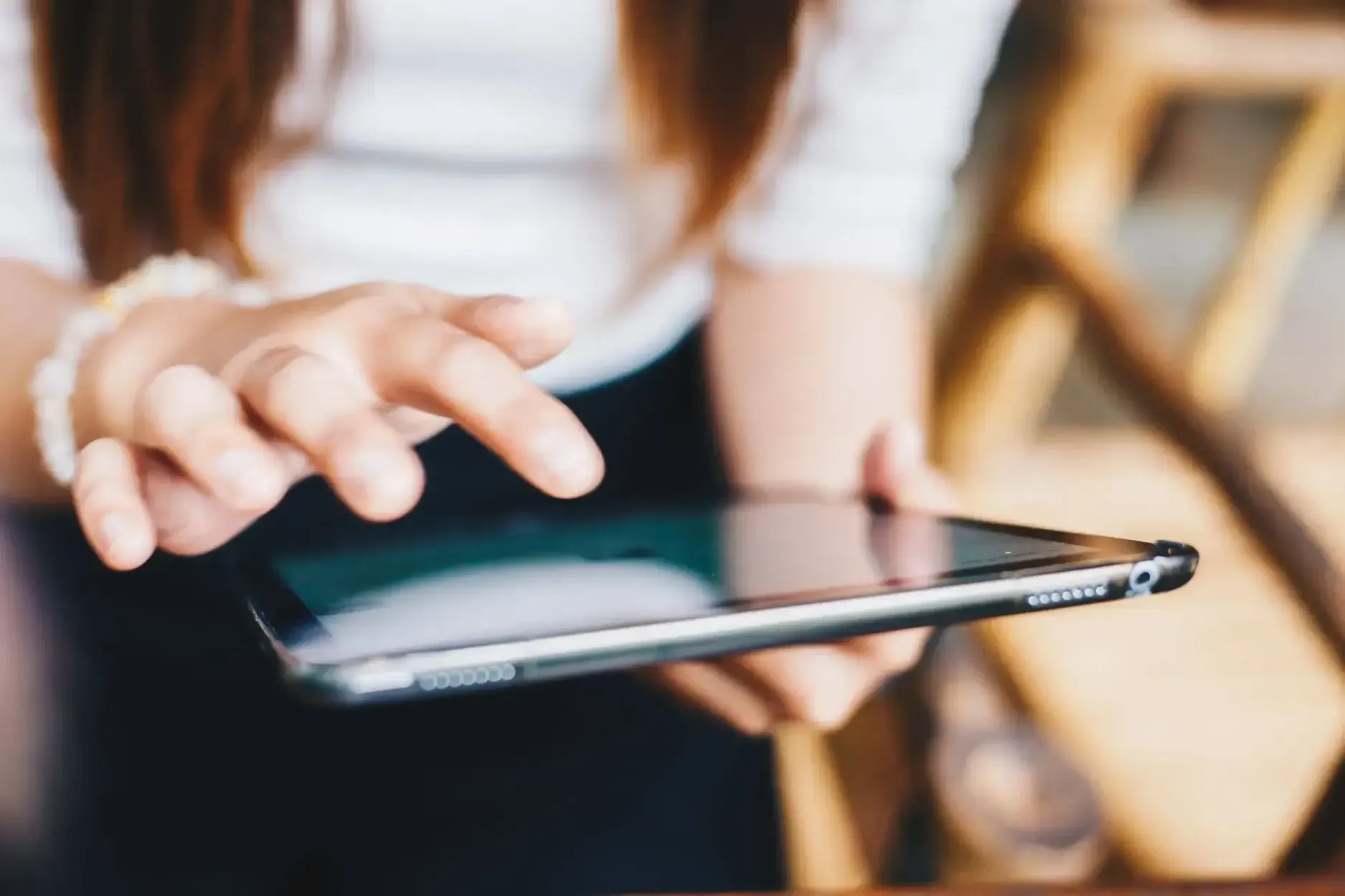 Person using a smartphone with a hand tapping the screen indoors
