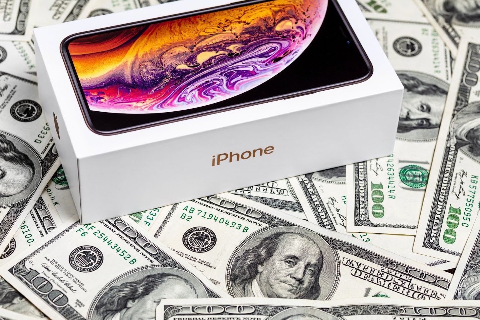 IPhone box on top of scattered U.S. dollar bills