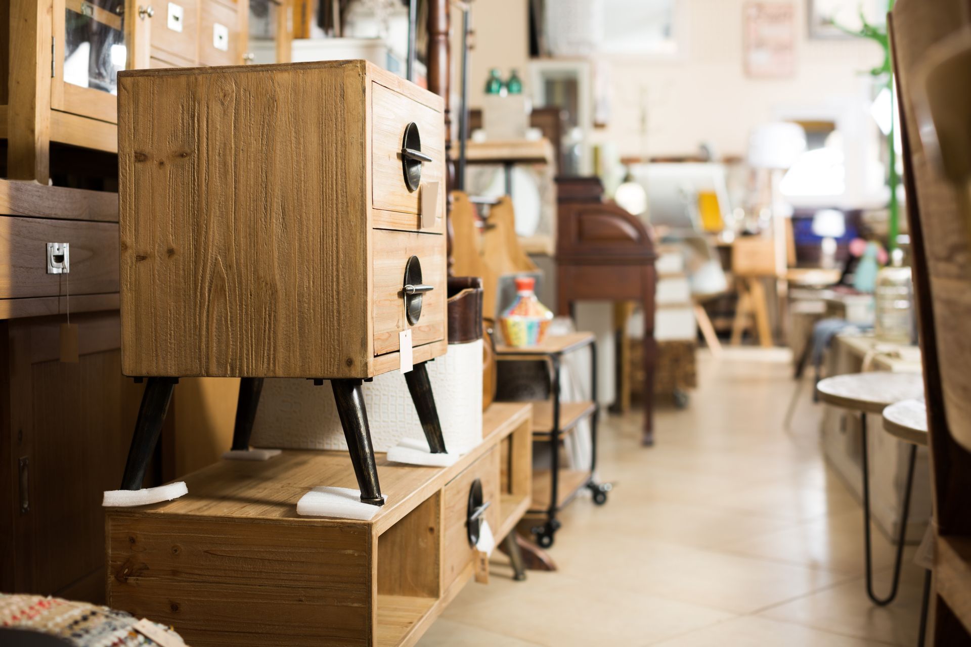 Wooden nightstand with two drawers displayed inside a furniture store showroom.