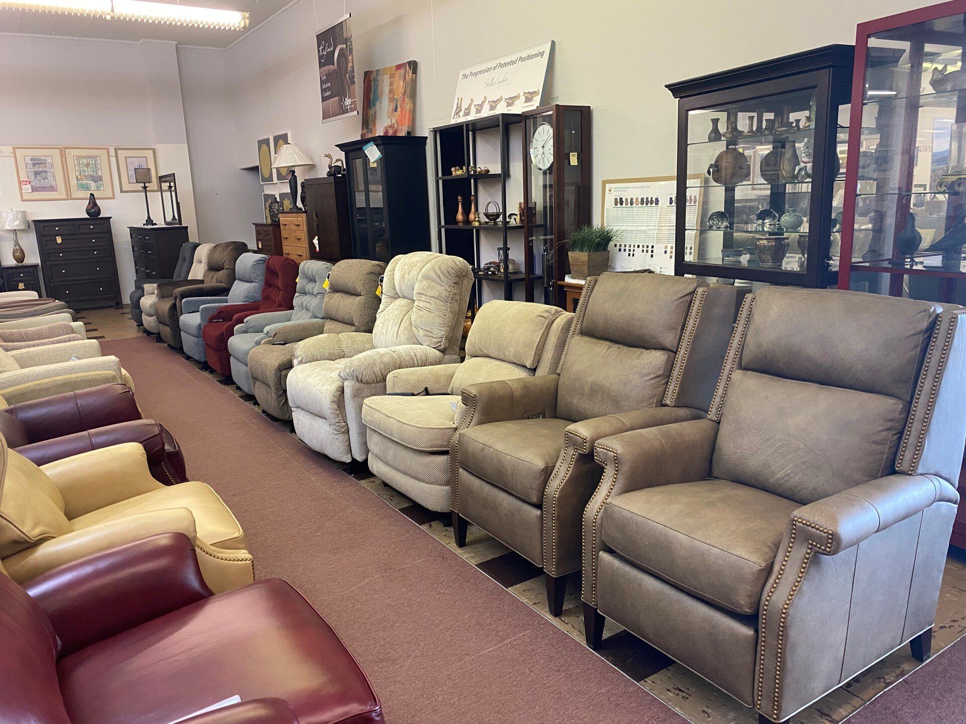 A showroom filled with rows of various recliner chairs, displayed on a carpeted floor in a furniture store.