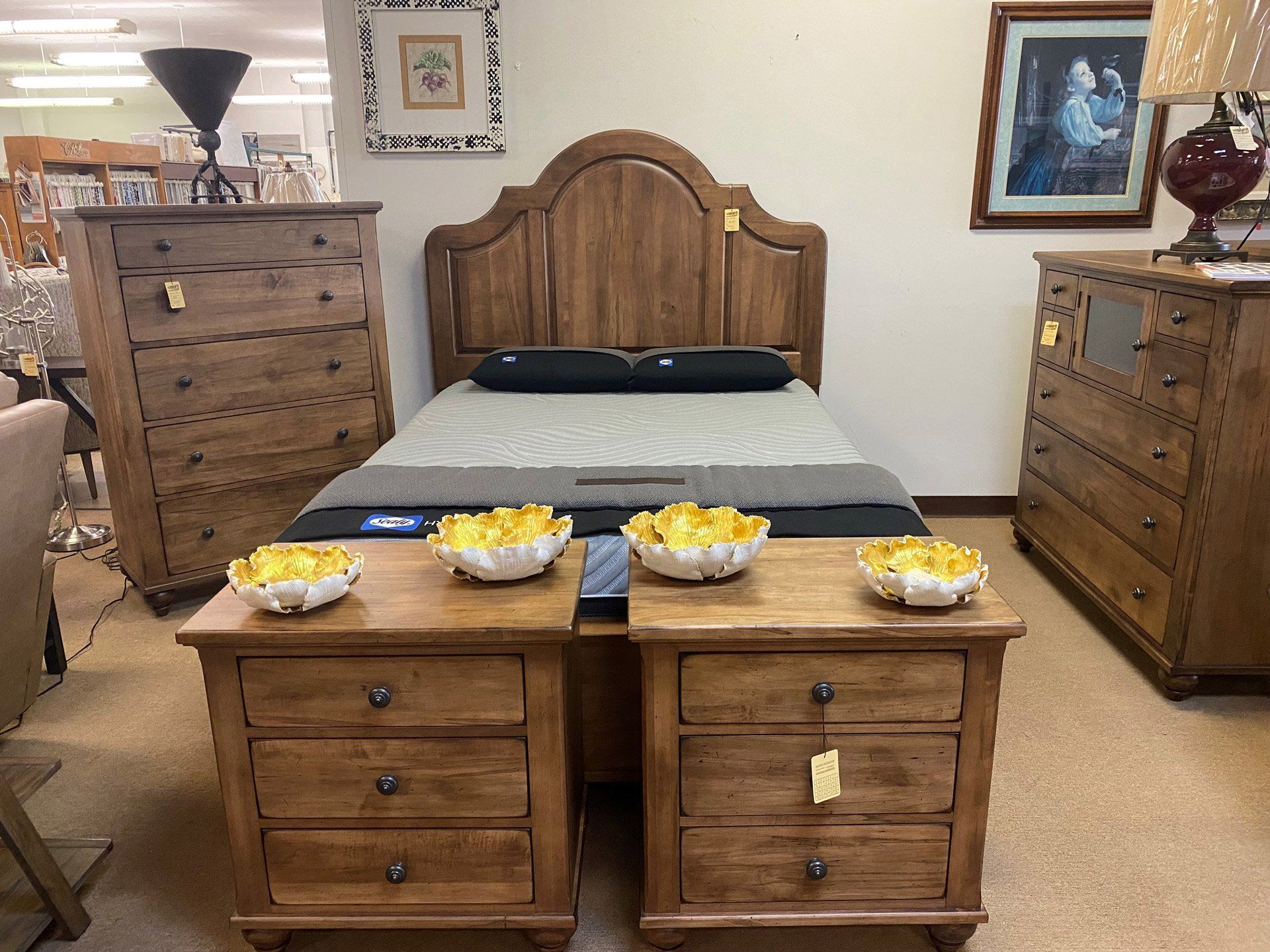 A wooden bedroom furniture set including a bed, two nightstands, and two dressers displayed in a showroom.