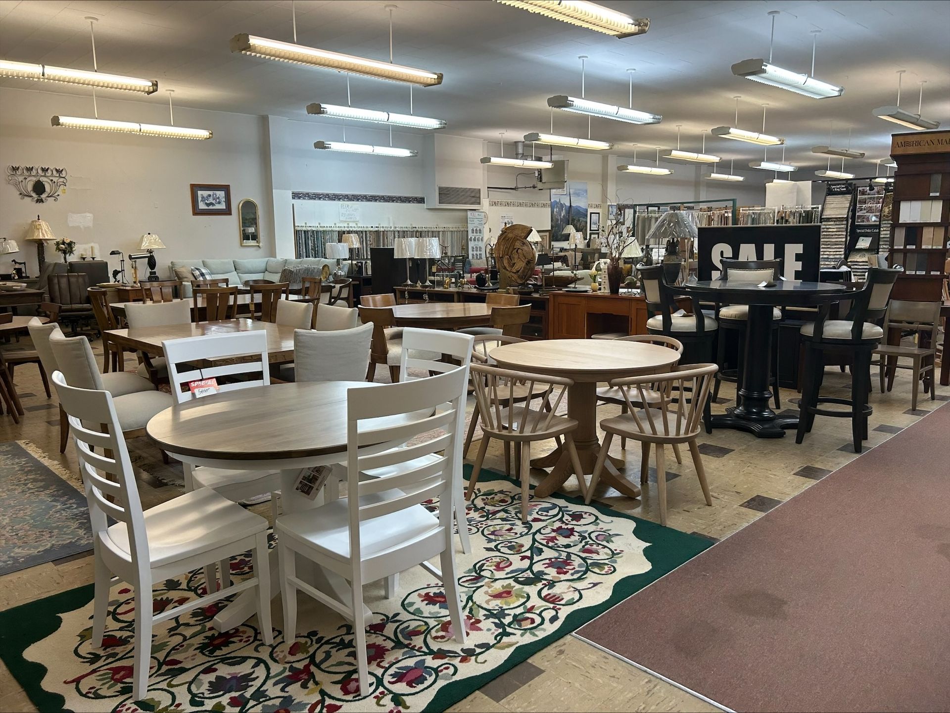 Antique store with white tables, chairs, and lamps under bright ceiling lights.