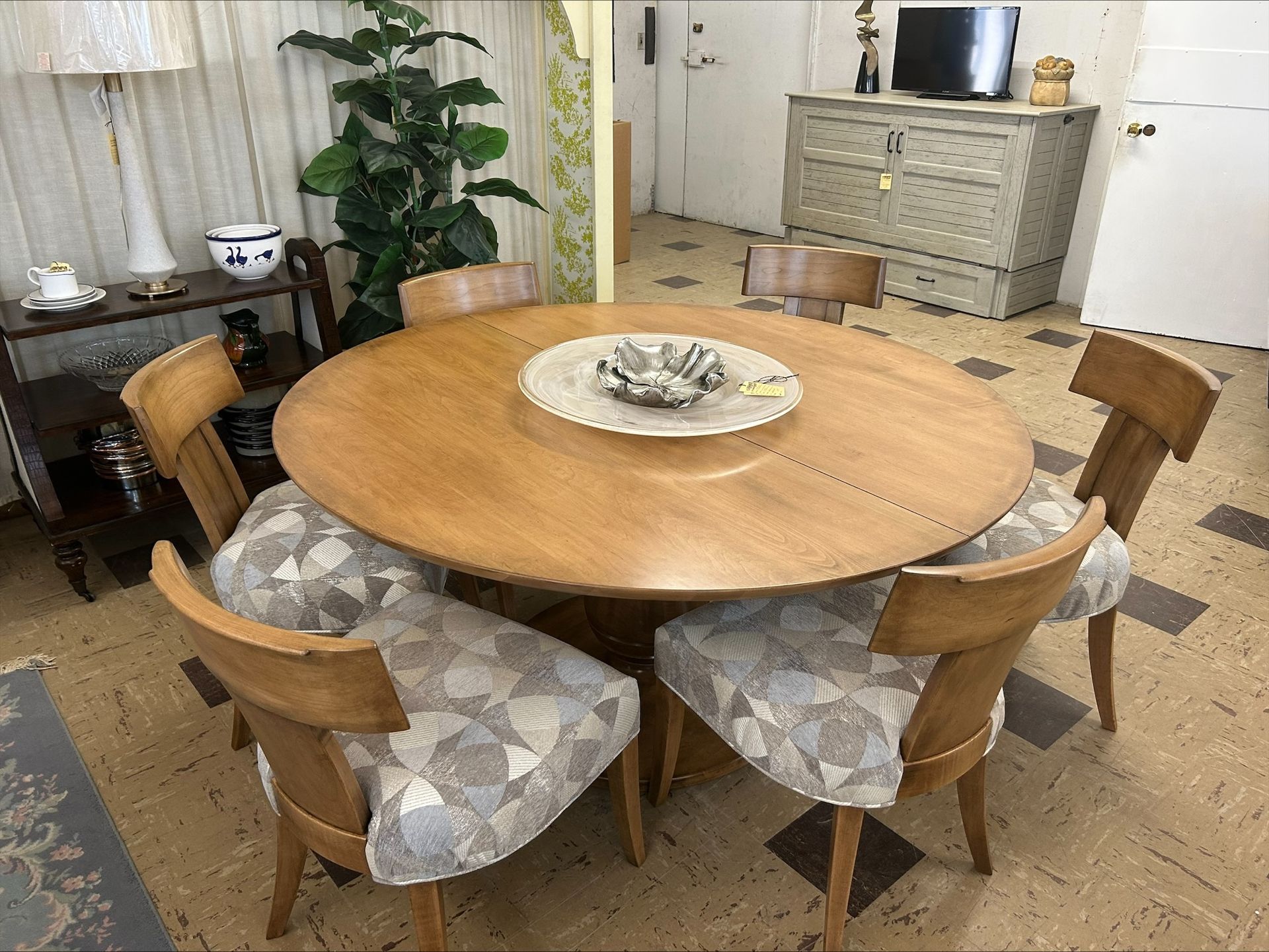 Round wooden dining table with four upholstered chairs in a bright room