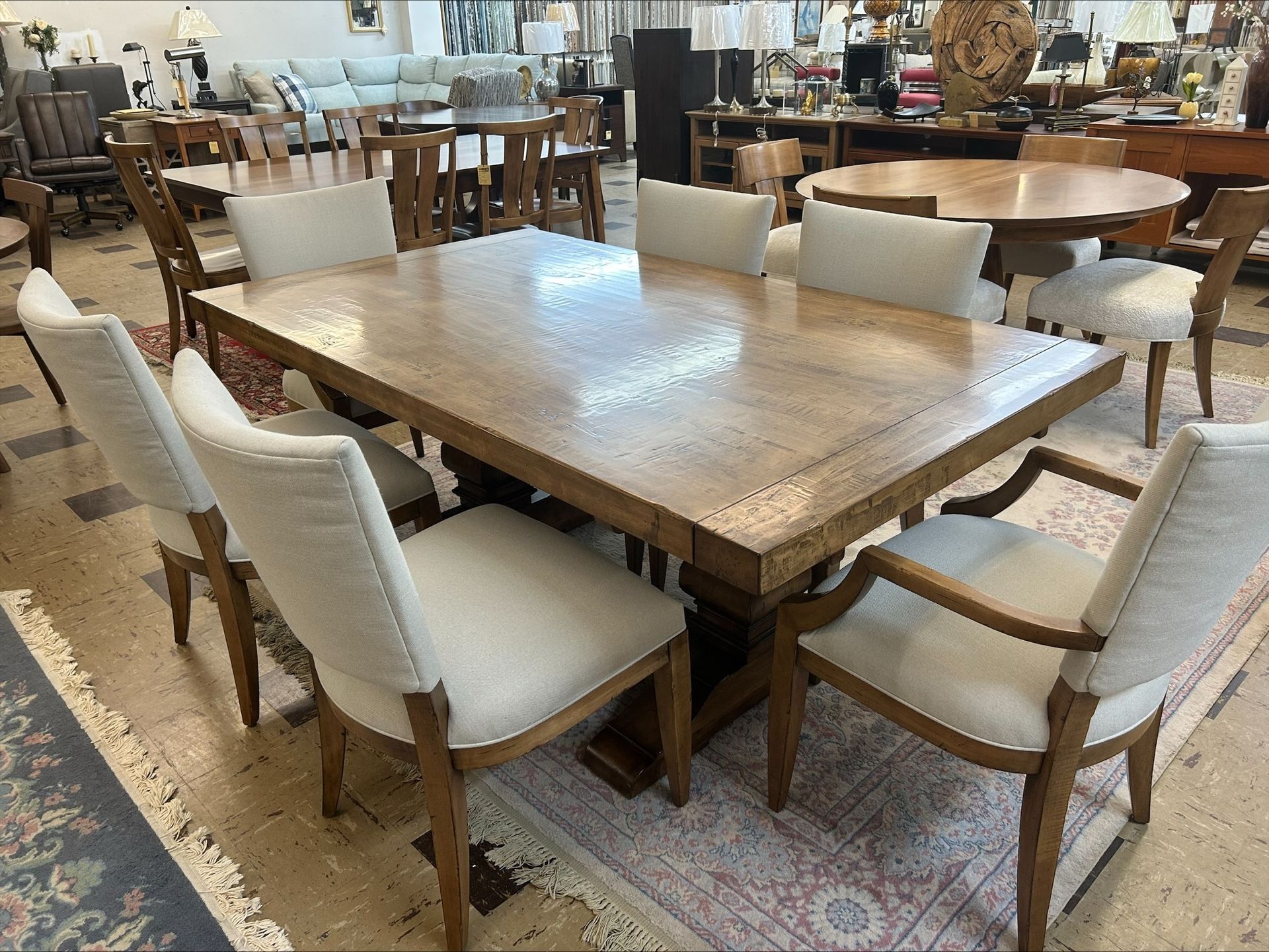 Furniture showroom with a large wooden table surrounded by upholstered chairs and ottomans