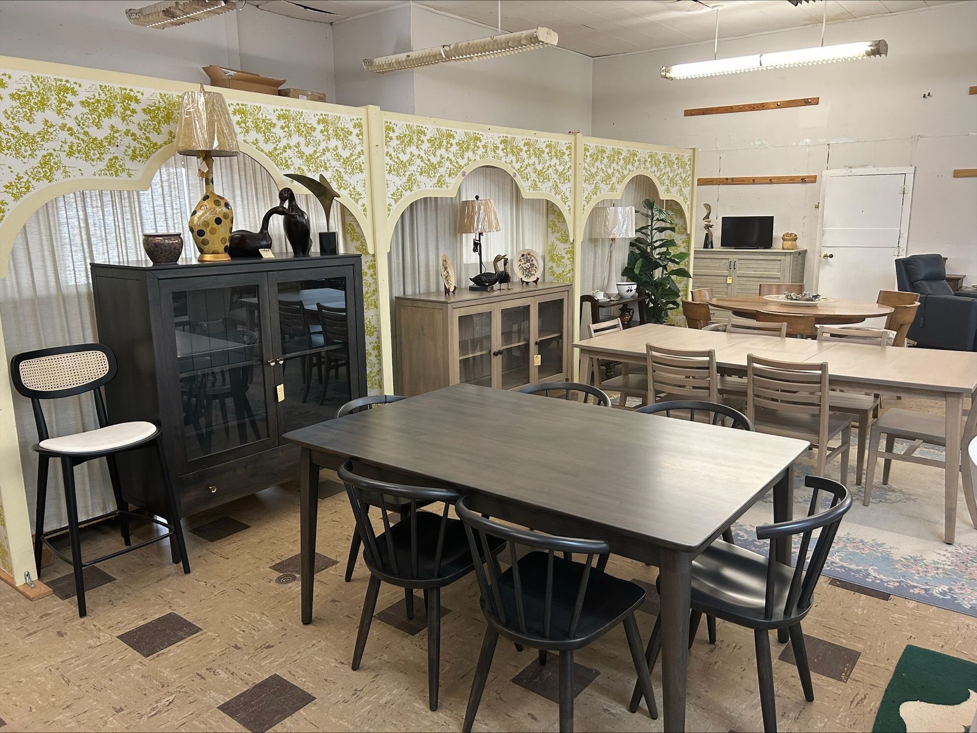 Cozy classroom with tables, chairs, cabinets, and shelves under a decorative archway divider.