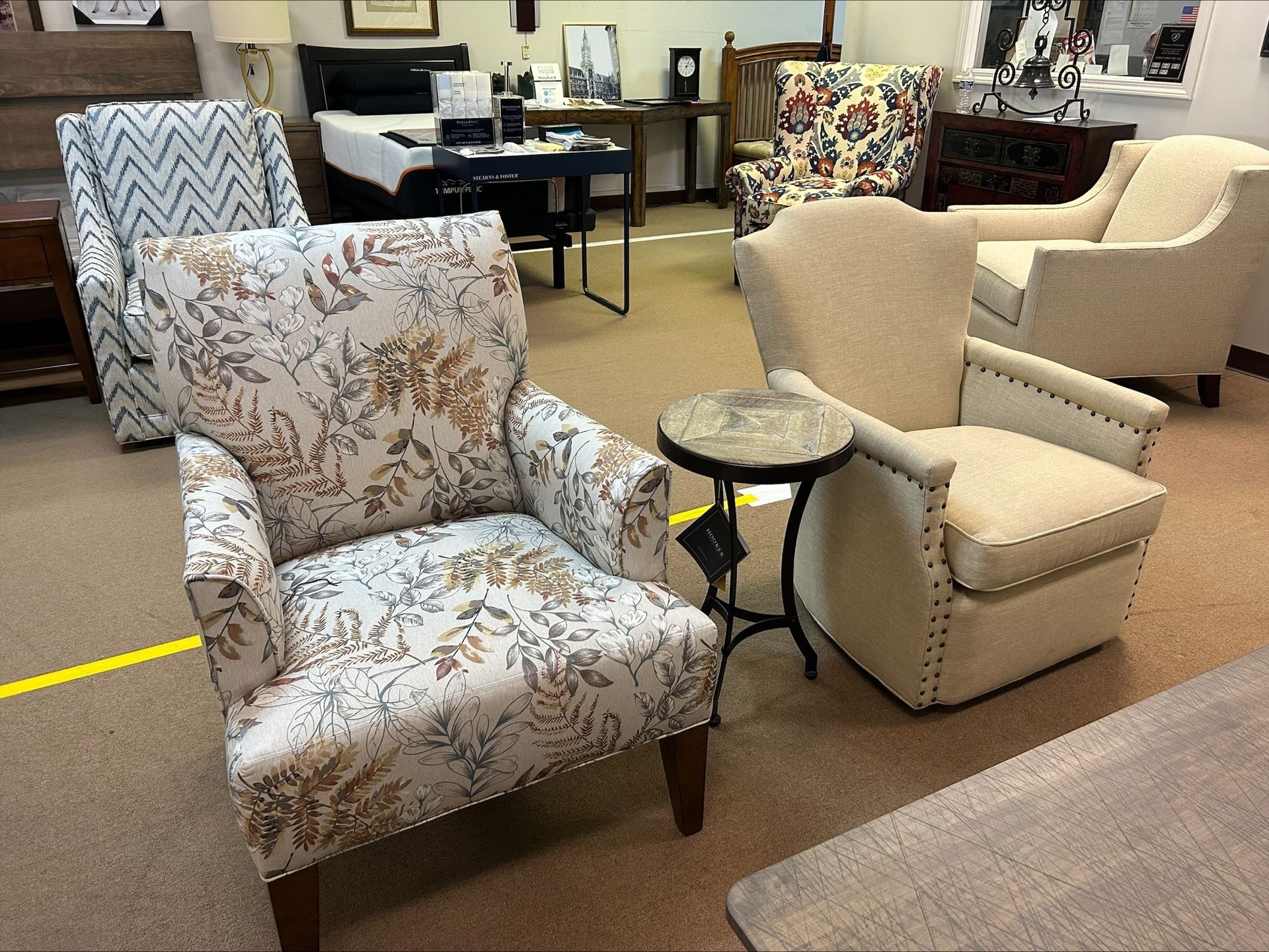 A showroom display featuring several upholstered armchairs with varied patterns and textures, set on a carpeted floor.