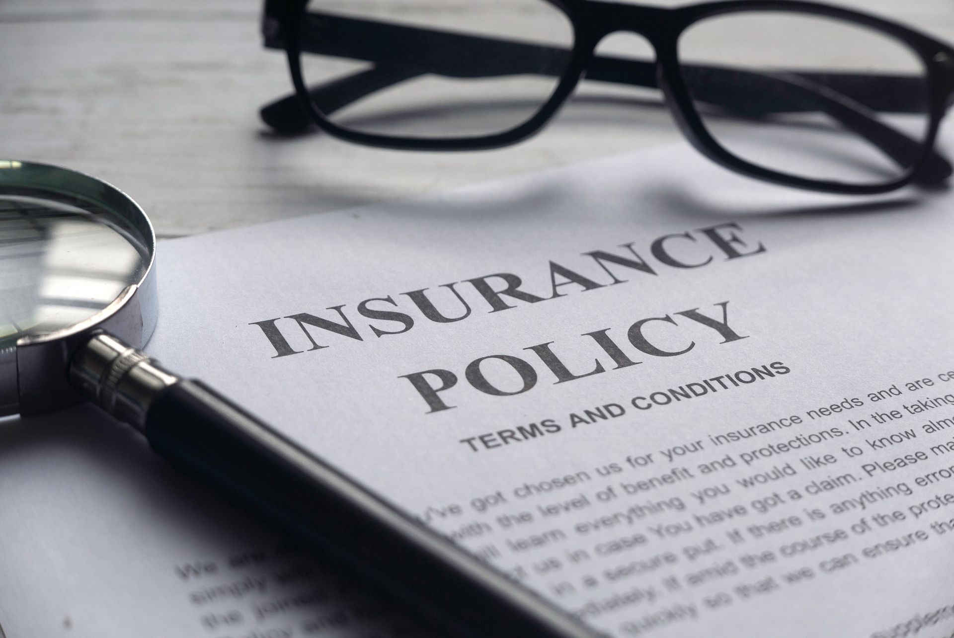 A magnifying glass is sitting on top of an insurance policy.