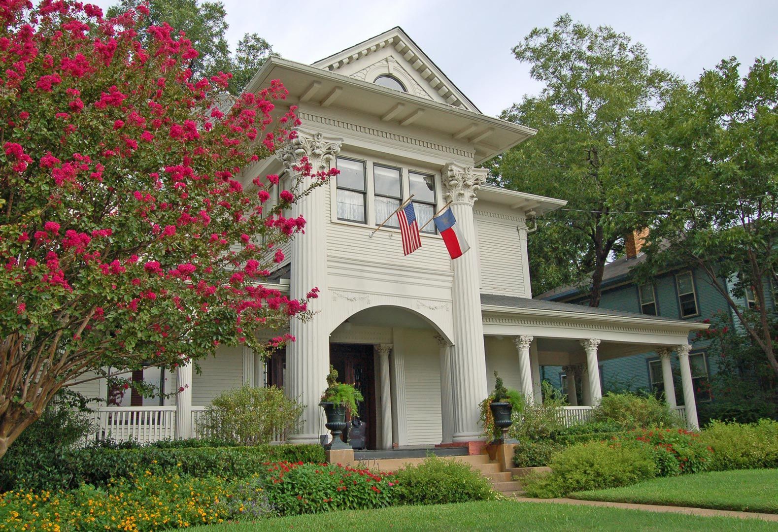 A white house with a red white and blue flag on the porch