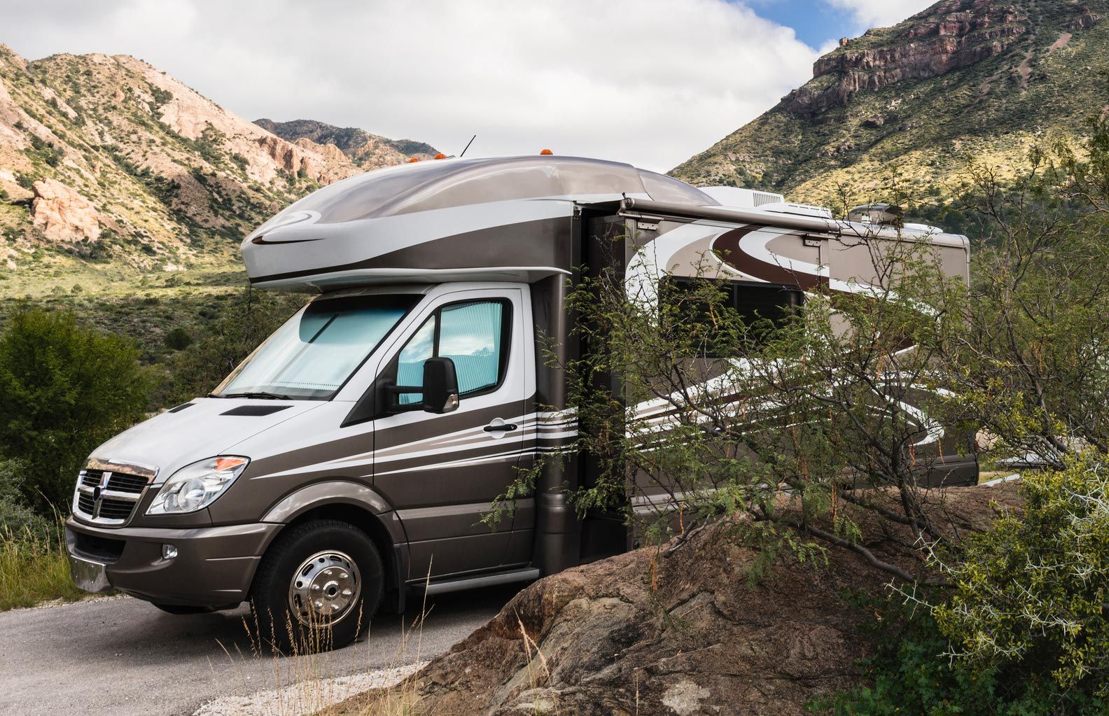 A rv is parked on the side of a road in the mountains.
